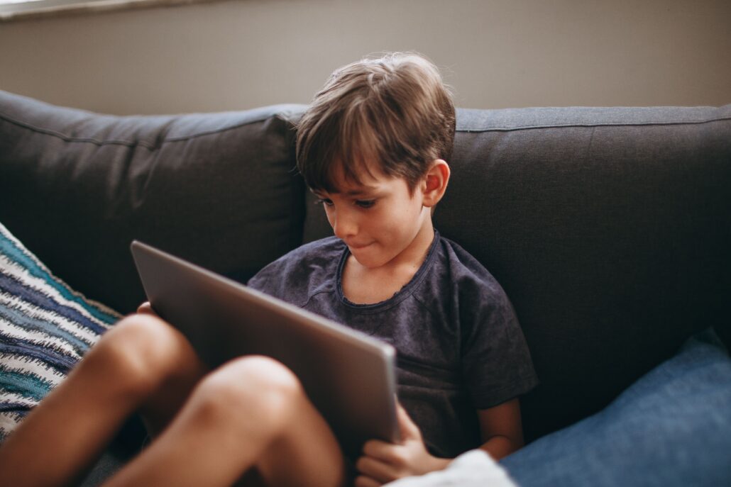child in sensory overload using ipad for screen time on the couch