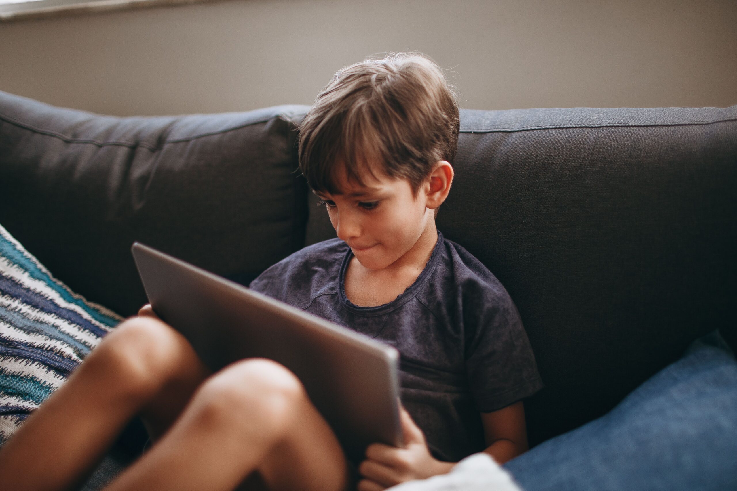 child in sensory overload using ipad for screen time on the couch