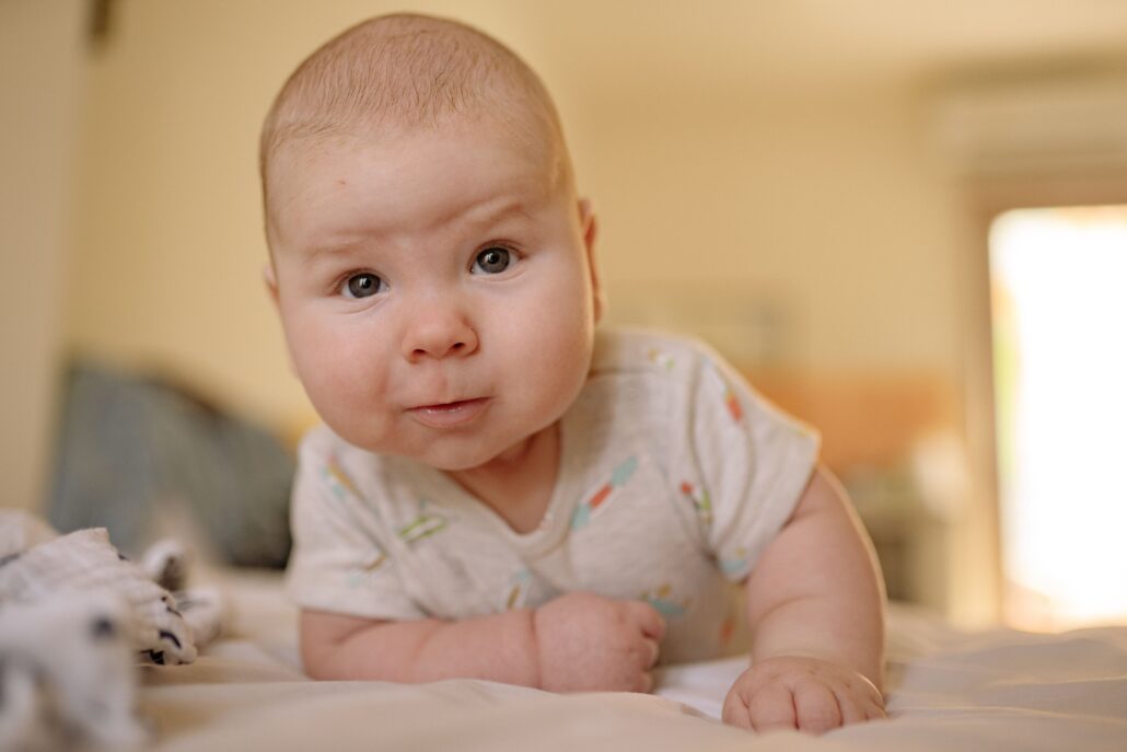 infant or baby lifting head, leaning slightly and turning head to one side