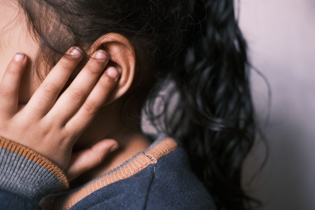 close up of child holding ear because of ear infection